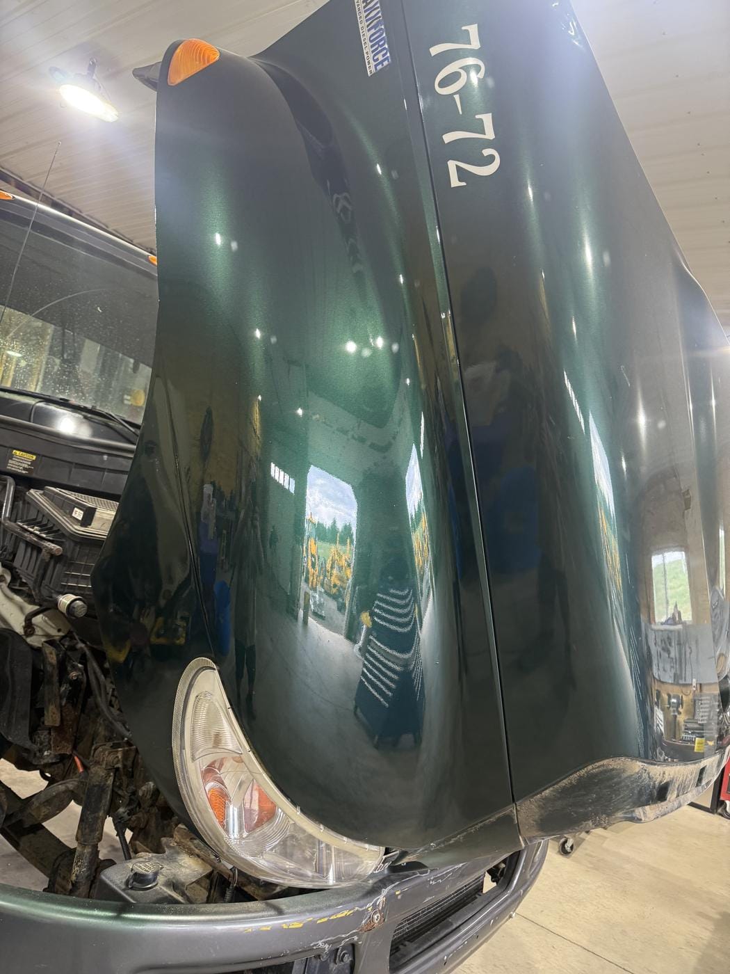 A pickup hood and fender in fresh dark green paint.