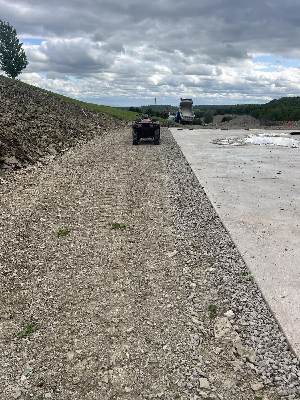A gravel lane along a new slab, with a dump truck at the far end.