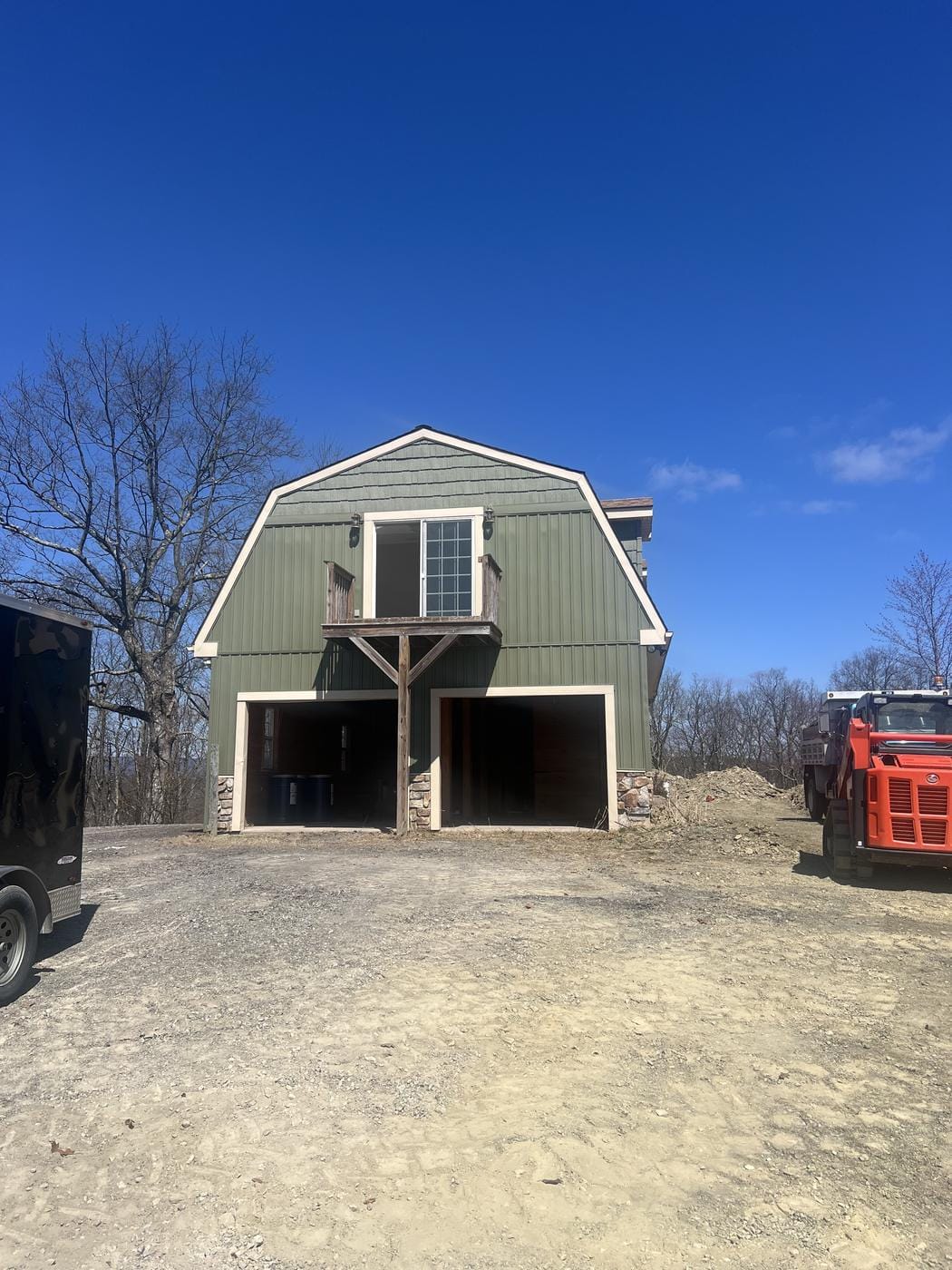 Fresh ground around a two-bay garage, with the dump truck at right.