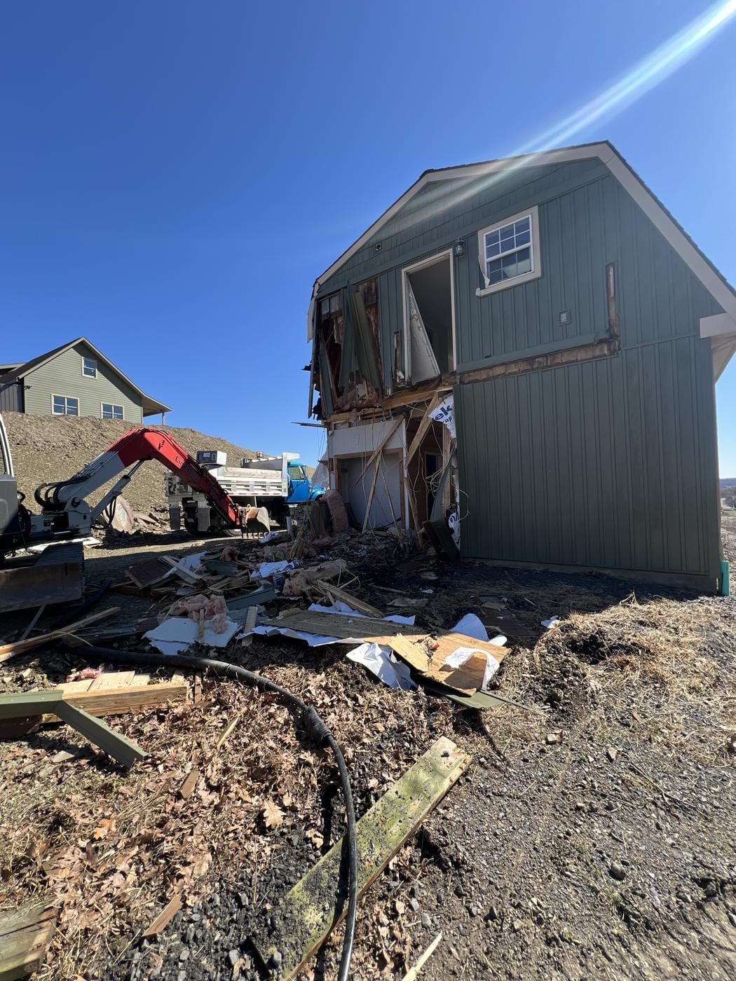 What is left of a building mid tear-down, with the excavator beside it.